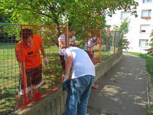 Dobrovoľníci natierajú plot